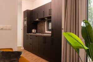 A modern kitchen with dark cabinetry, a stove, and a window with curtains.