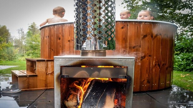 Ett bubbelbad med en träpanel på utsidan och en synlig eld som brinner inuti.