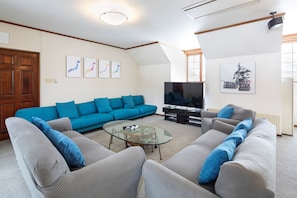 A living room with a sectional sofa, a glass coffee table, a flat-screen TV, and artwork on the walls. - Snowgum Lodge (Kutchan)