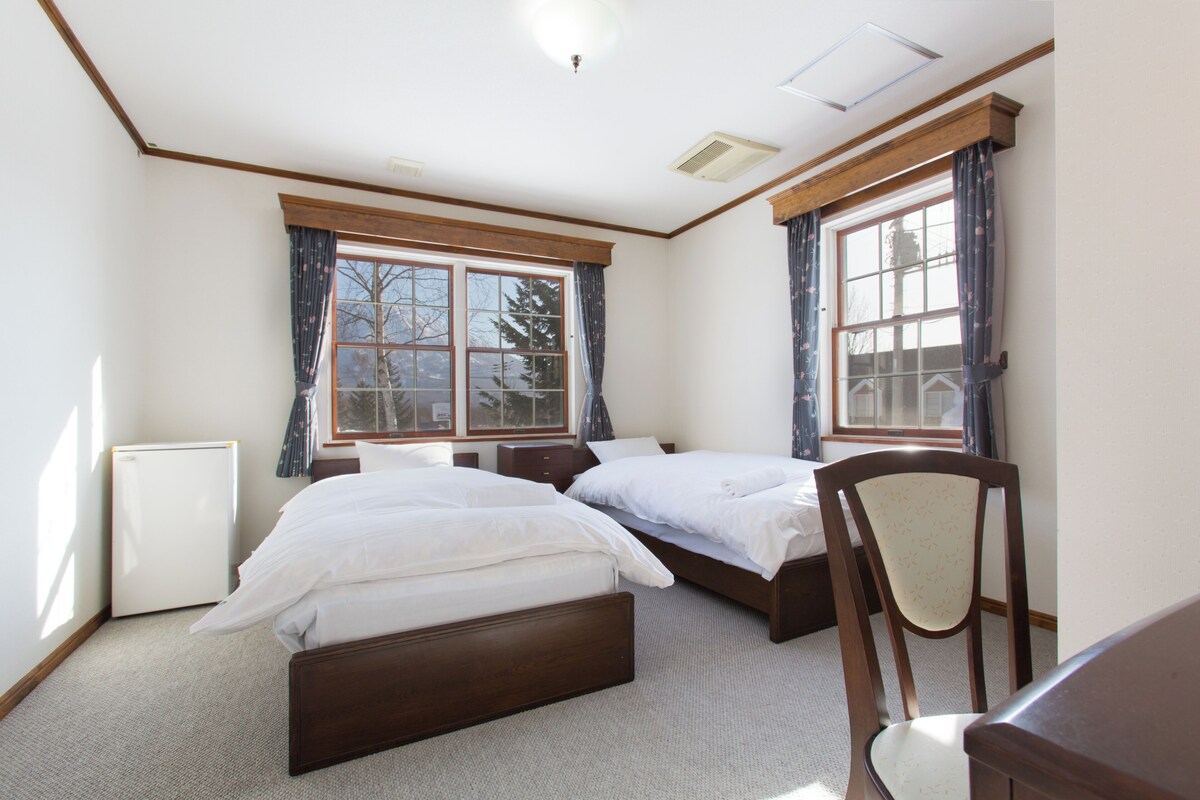 A bedroom with two beds, a chair, and a radiator.