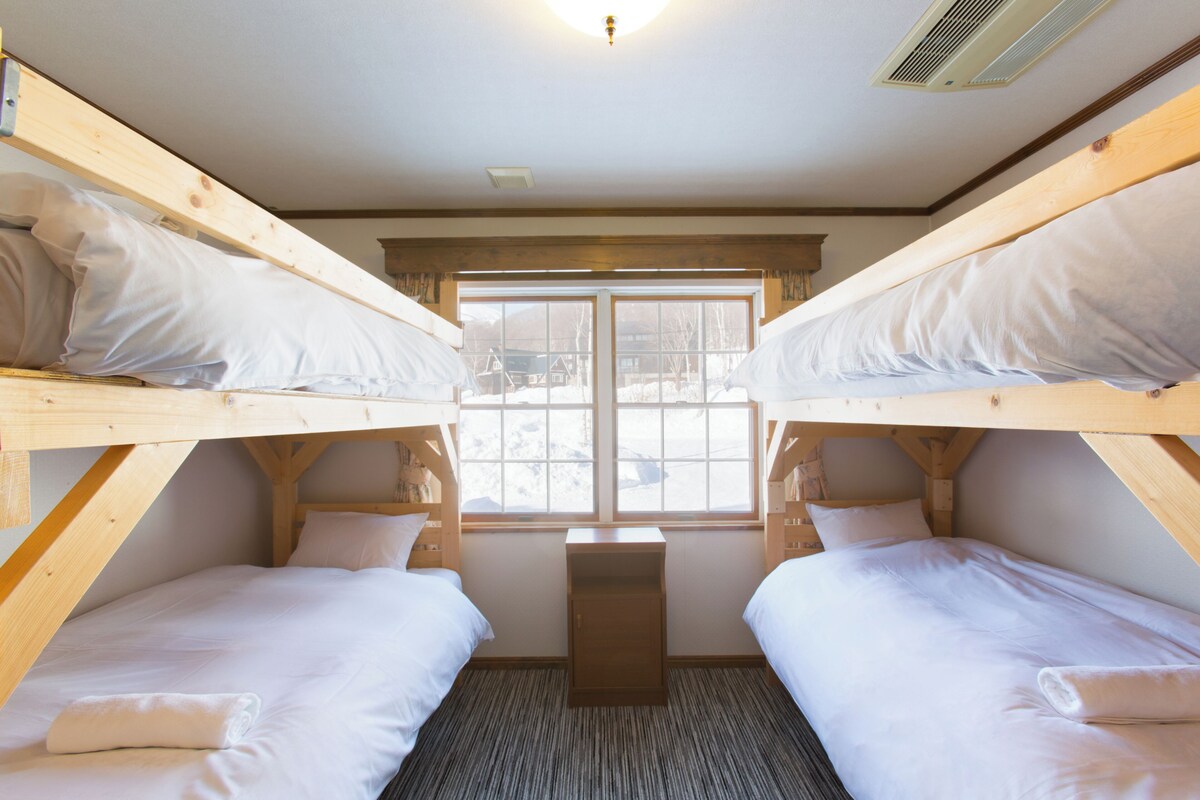 A bunk bed room with a window, a small desk, and a radiator.