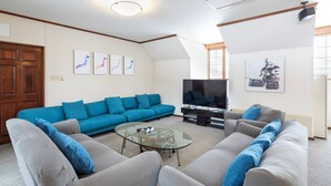 A living room with a sofa set, a glass coffee table, a flat-screen TV, and artwork on the walls.