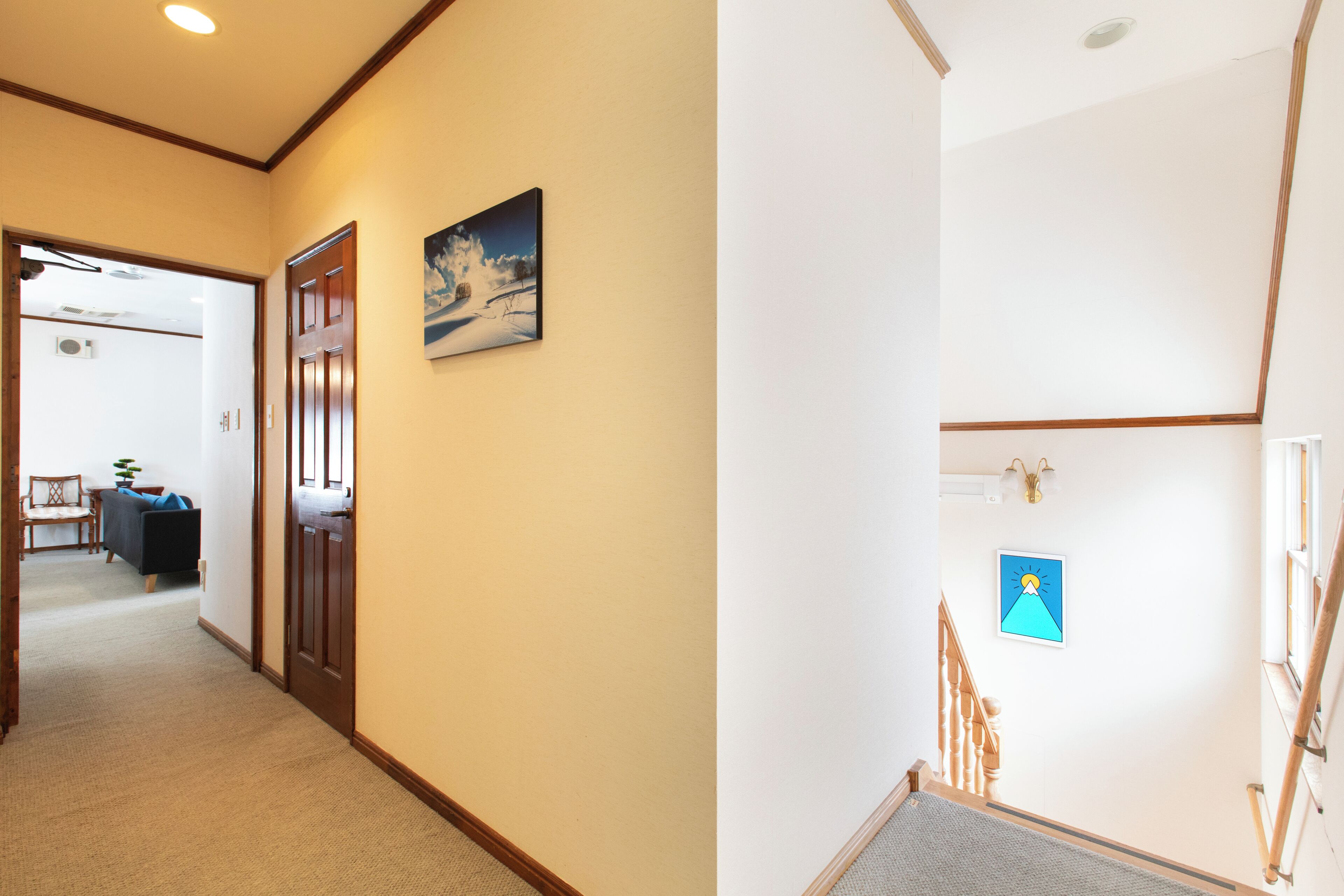 A hallway with a door, a framed picture, and a staircase with a railing.