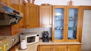 Une cuisine avec des meubles en bois, un four à micro-ondes, une machine à café et un meuble vitré contenant de la vaisselle.