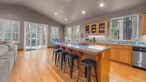 A spacious kitchen with a large island, wooden cabinets, and a stainless steel dishwasher. - Thunderbird Nest Hot Tub EV charger (South Lake Tahoe)