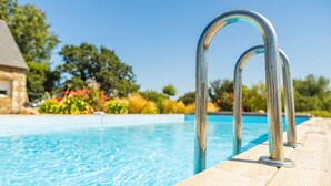 Une piscine dotée de rampes métalliques et d’une plage en bois.