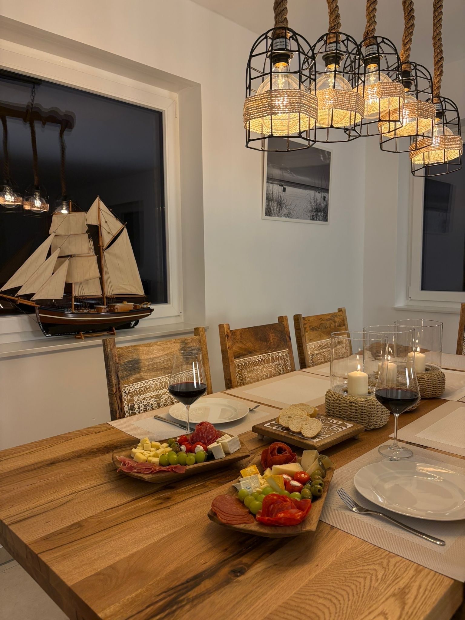 Ein Esstisch mit Holzausstattung, umgeben von Stühlen, einem Schiffmodell und einer Kristallleuchter.