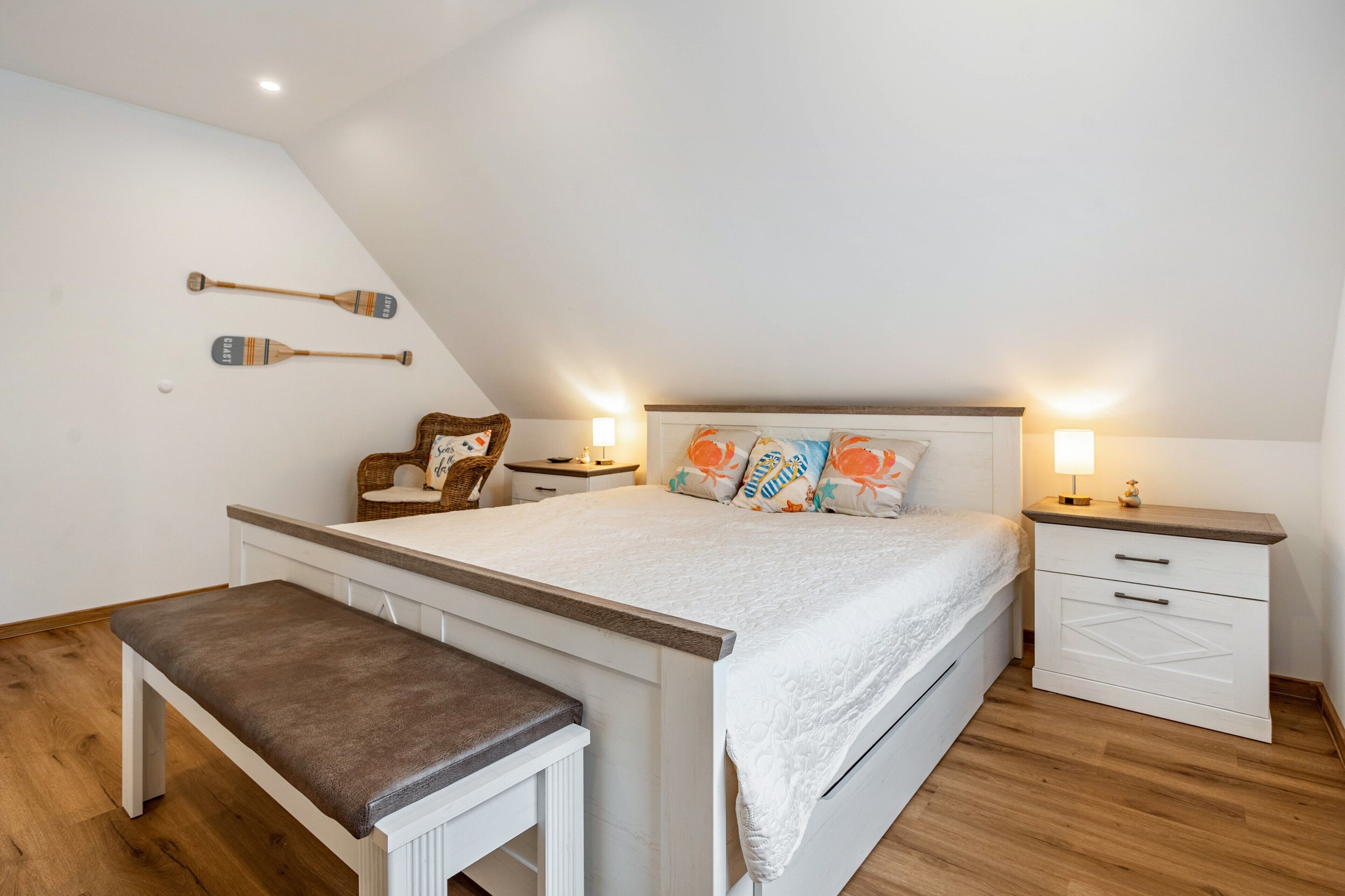 Ein Schlafzimmer mit einem Bett, Nachttischen, einer Bank und Gegenständen an der Wand.