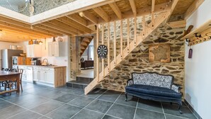 A spacious kitchen with modern appliances, a dining area with a wooden table, and a stone staircase leading to a loft. - "Parentezenn" cottage - for 15 people (Plésidy)