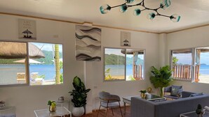 Un vaste espace de vie comprenant un canapé, des fauteuils, une table basse et une vue sur la mer.
