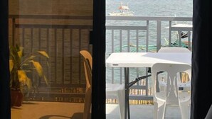 Un balcon avec vue sur un lac et des montagnes, une table, des chaises et une plante en pot.