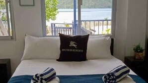 Un lit avec une couette bleue, des oreillers blancs, un oreiller noir orné du mot « BURBERRY » et des serviettes pliées.