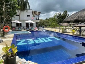 A swimming pool with the word 'LOVE' spelled out in tiles, surrounded by lounge chairs and umbrellas. - Lopez Beach Resort (Sipalay)