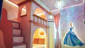 Une chambre d’enfant avec un lit en forme de château, une fresque représentant une princesse et un lustre.