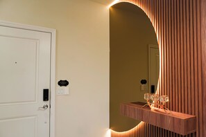A room with a white door, a wall-mounted light fixture, and a mirror reflecting part of the room. - 5BR Themed Villa · Pool · Windsor Cay · Disney (Clermont)