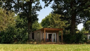 A small wooden cabin with a porch, surrounded by trees and grass. - Cottage with Scenic Pasture Outlook (Zuna)