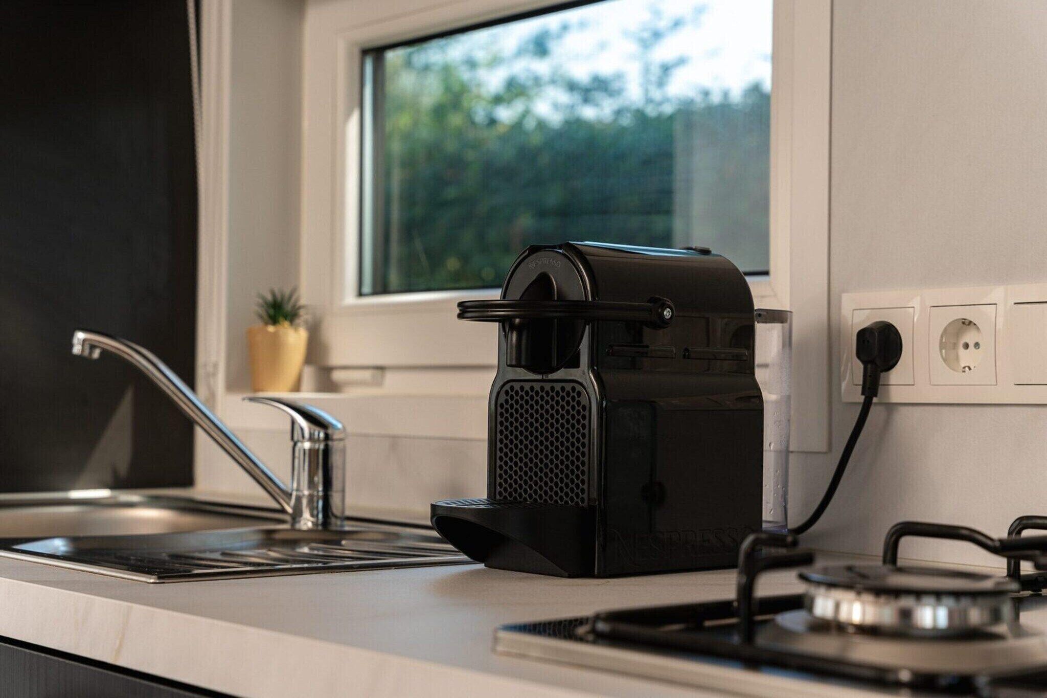 A kitchen with a coffee maker, a sink, and a window.