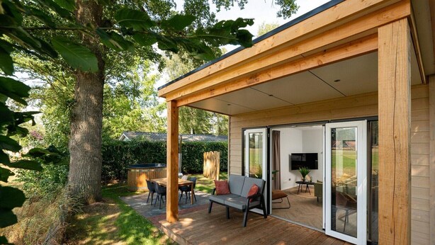 A covered outdoor area with a wooden deck, a sofa, and a TV. - Cottage with Scenic Pasture Outlook (Zuna)