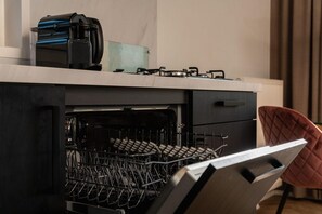 Une cuisine équipée d’un lave-vaisselle, d’une machine à café et d’une cuisinière à gaz.