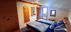 Ein Schlafzimmer mit zwei Betten, Holzwänden, einem großen Spiegel und einem Fenster mit Vorhängen.
