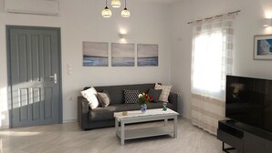 Ein Wohnzimmer mit einer Couch, einem Couchtisch, einem Fernseher und Kunstwerken an der Wand.