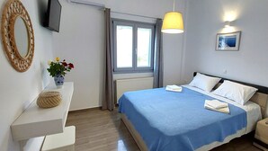 Quarto com cama, mesa de cabeceira, abajur e janela com cortinas.
