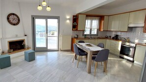 Cozinha moderna com área de refeições, lareira e vista pela porta de vidro.