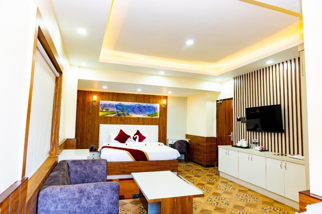 A hotel room with a bed, a sofa, a TV, a desk, and a cabinet.