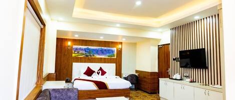 A hotel room with a bed, a sofa, a TV, a desk, and a cabinet.