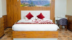 Un dormitorio con cabecera de madera, una cama con almohadas rojas, un escritorio y una silla.