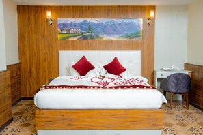 Un dormitorio con cabecera de madera, una cama con almohadas rojas, un escritorio y una silla.