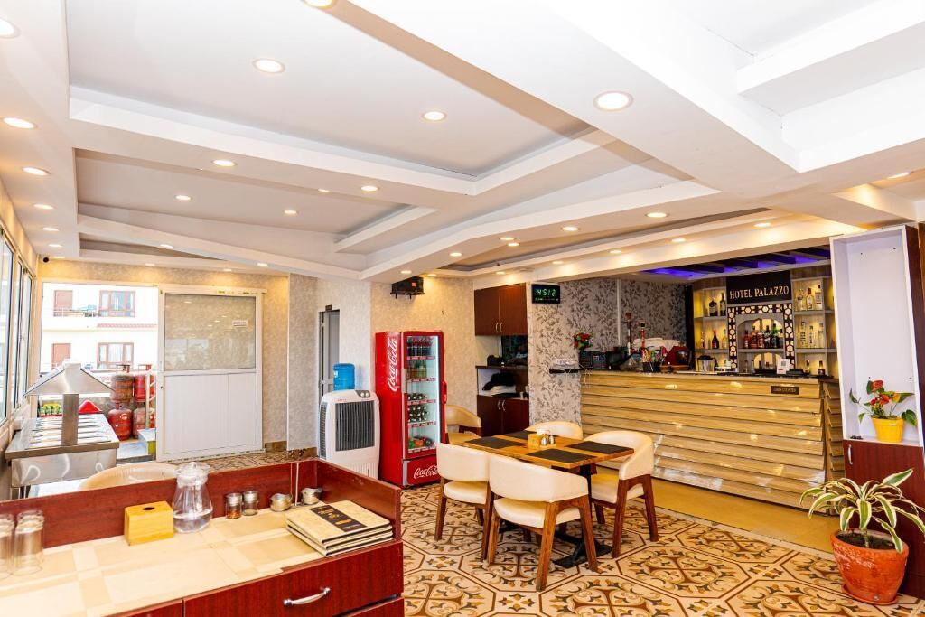 Un hall d’hôtel comprenant un comptoir d’accueil, un réfrigérateur à boissons Coca-Cola, un bar et un espace repas avec des chaises et une table.