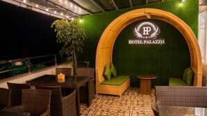 Un área de estar con mobiliario de mimbre, una pared verde con un logotipo y un suelo estampado.