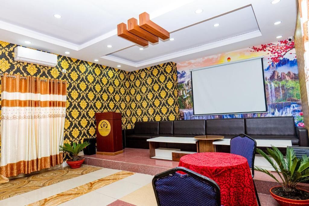 Un vestíbulo con papel tapiz estampado, un atril, una zona de estar y una pantalla de proyección.