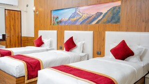 Habitación de hotel con dos camas, cada una con ropa de cama blanca y detalles en rojo, cabeceros de madera y un cuadro con paisaje de montaña en la pared.