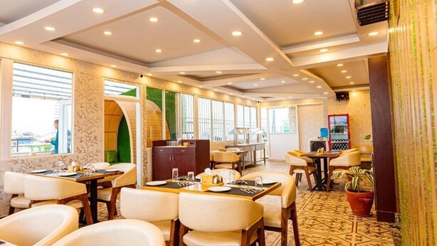Un restaurante con mesas y sillas, un suelo con diseño y vistas amplias a través de grandes ventanales.