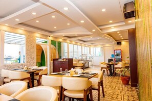 Un restaurante con mesas y sillas, un suelo con diseño y vistas amplias a través de grandes ventanales.