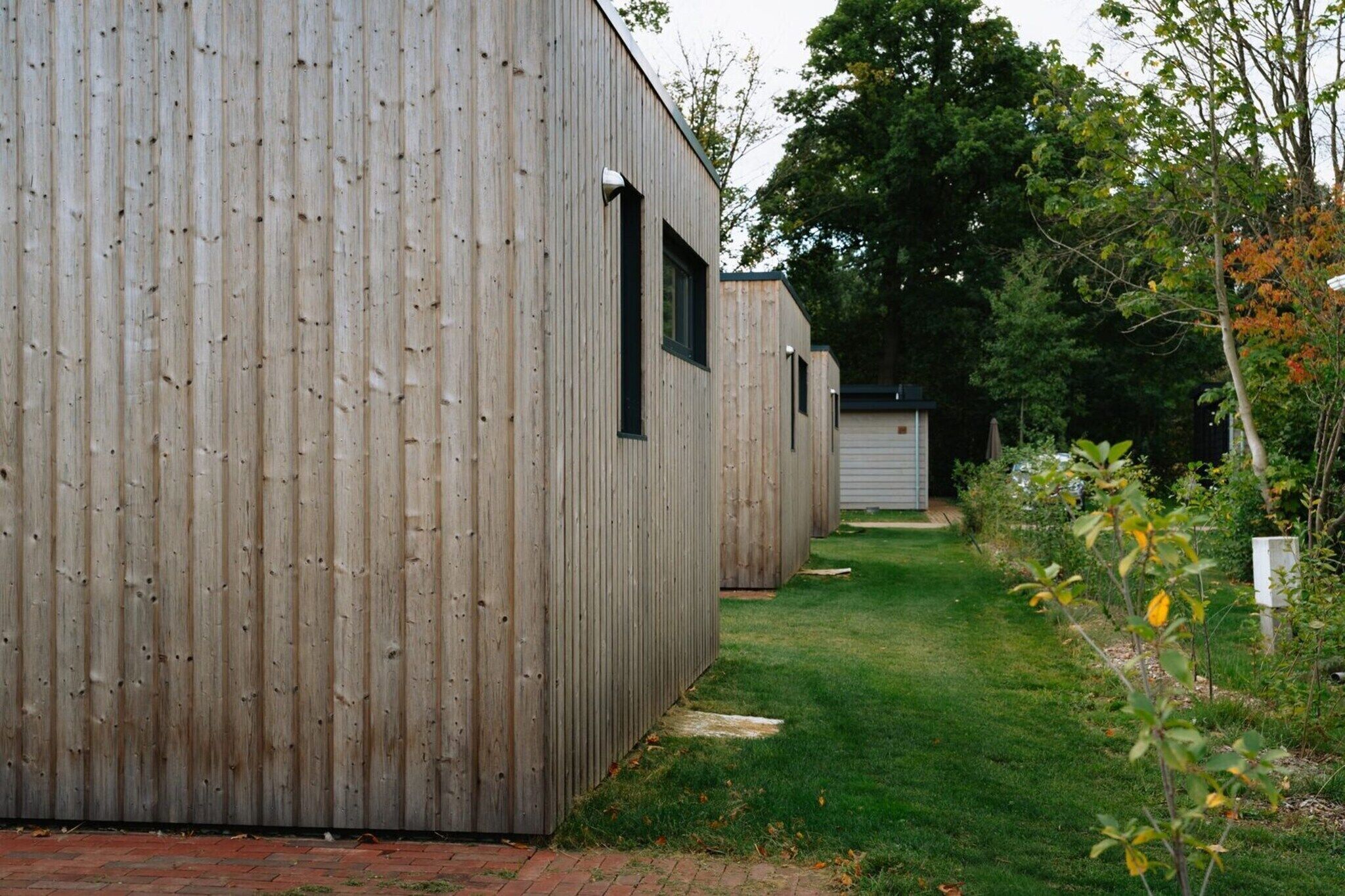 A row of wooden buildings with a grassy pathway between them.