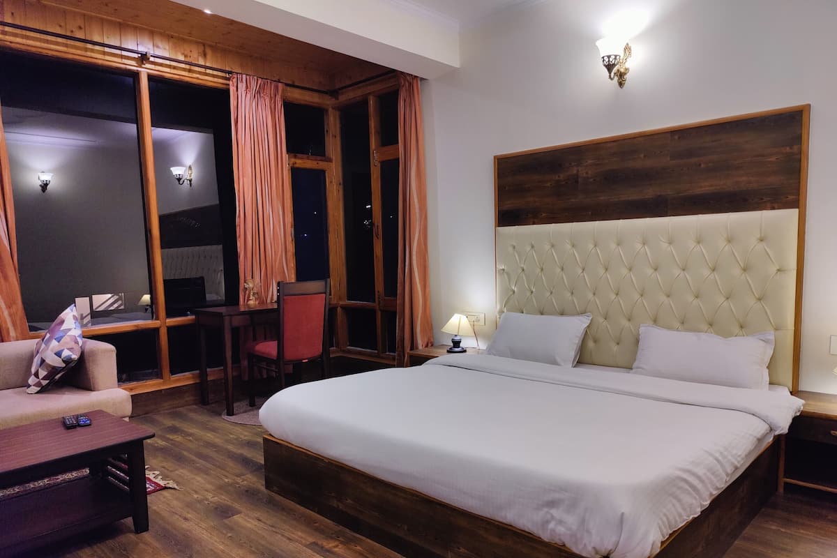 Un dormitorio con una cama grande, un cabecero de madera, un escritorio con una silla y un sofá.
