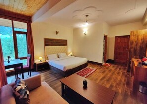 Een slaapkamer met een bed, nachtkastjes, een bureau, een stoel, een houten vloer en een deur.