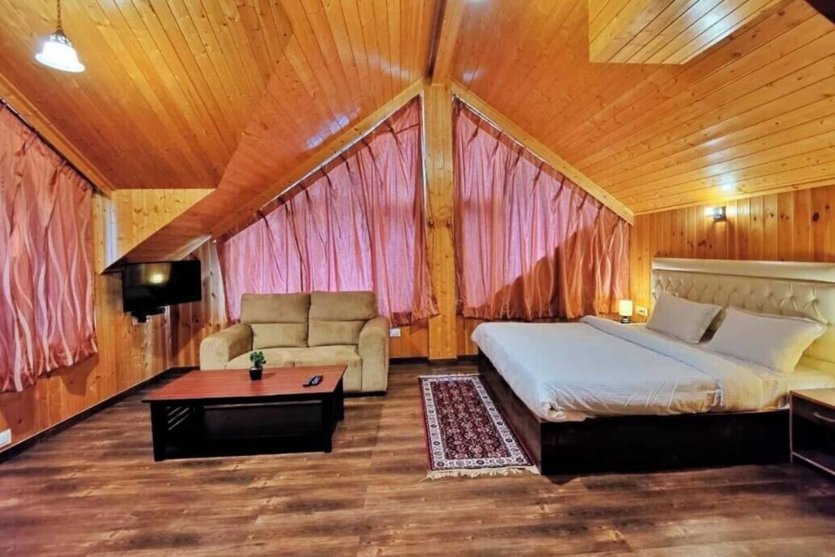 Un interior de madera con una cama, un sofá, una mesa de centro y un televisor.