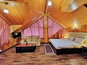 Een houten interieur met een bed, een bank, een bijzettafeltje en een televisie.