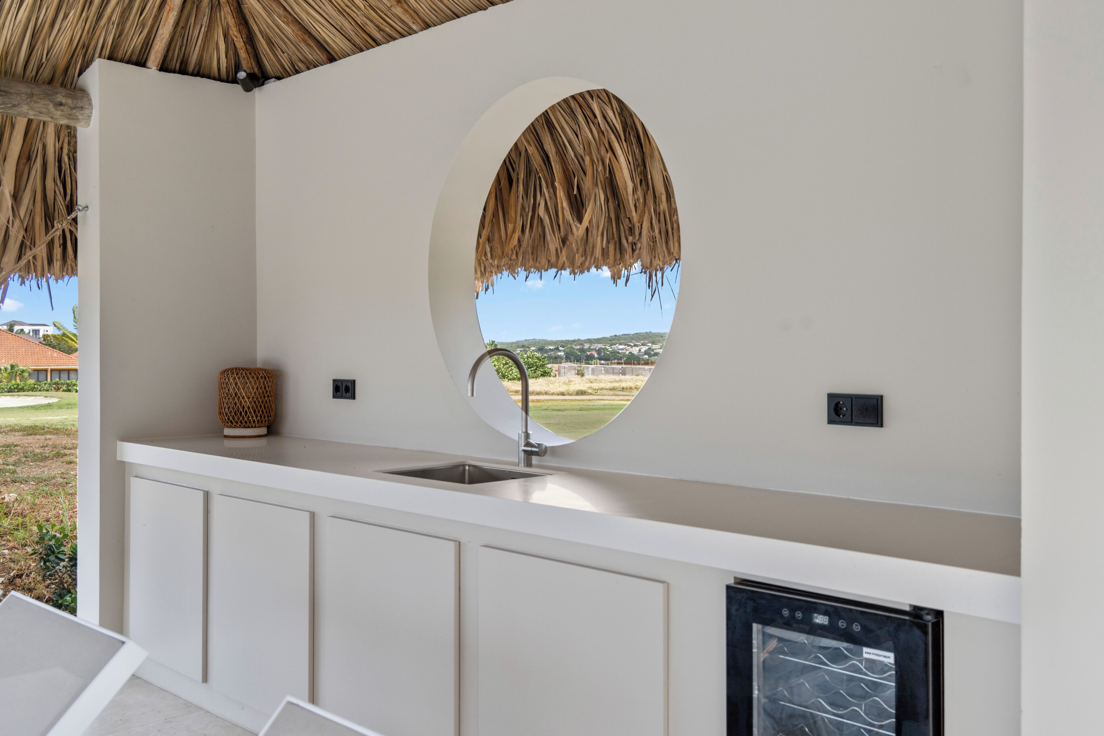 A kitchen with a circular window, a sink, and a built-in oven.