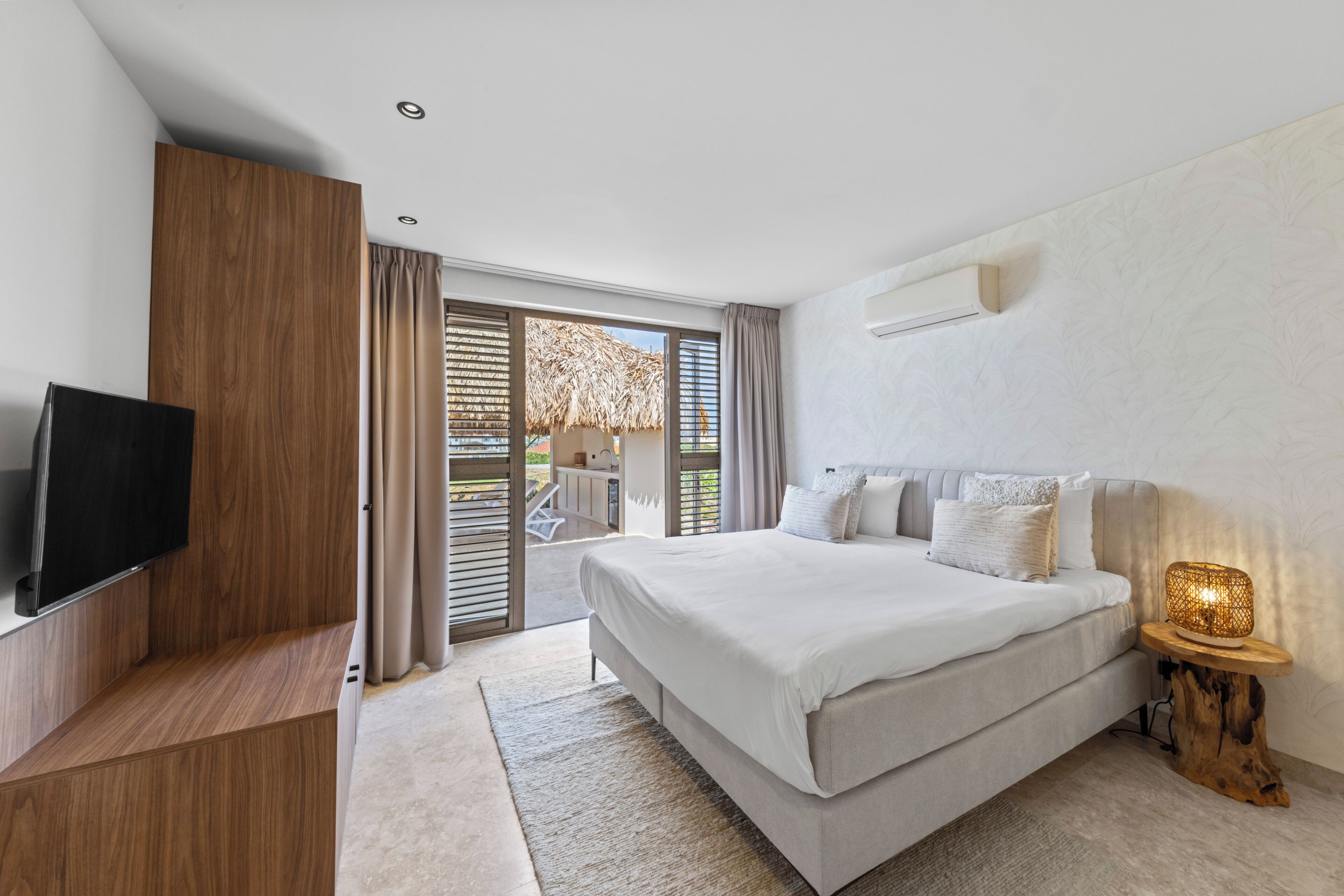Un dormitorio moderno con una cama grande, un televisor y una mesita de noche de madera.