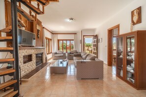 A spacious living area with a fireplace, sofas, a coffee table, and a bookshelf.