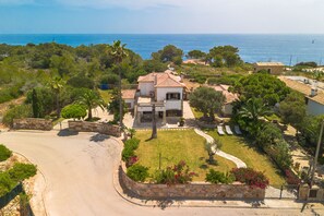A coastal property with a house, a paved driveway, and a stone wall.