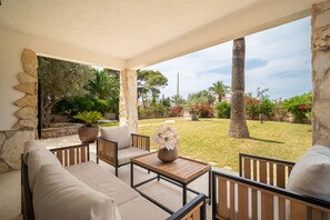 An outdoor patio with a sofa, chairs, a table, and a potted plant.