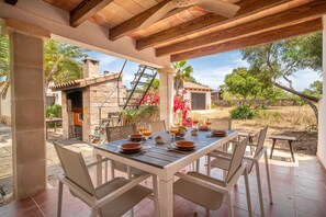 An outdoor patio with a table set for dining, stone architecture, and a view of the surrounding landscape.