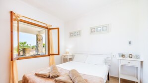 Habitación de hotel con cama, mesita de noche, espejo y vistas al exterior.