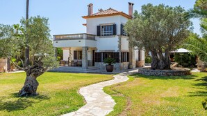Una casa de dos pisos con un camino de piedra que lleva a la entrada, rodeada de vegetación y árboles.